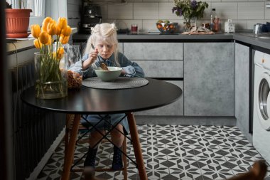 Mısır gevreği yerken kaşığa dikkatlice bakan kız.