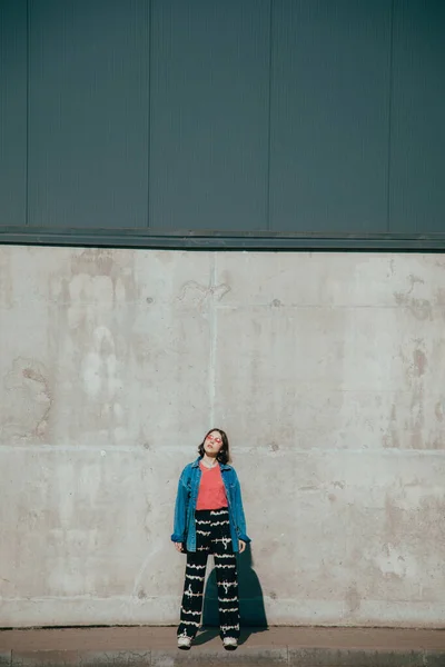 Hipster fille portant des lunettes de soleil debout devant le mur urbain et posant — Photo