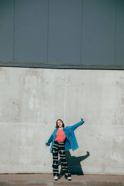 Ένα έφηβο κορίτσι να κρατάει ψηλά τα χέρια και να χαίρεται ενώ ποζάρει κοντά στο μεγάλο τοίχο. — Φωτογραφία Αρχείου