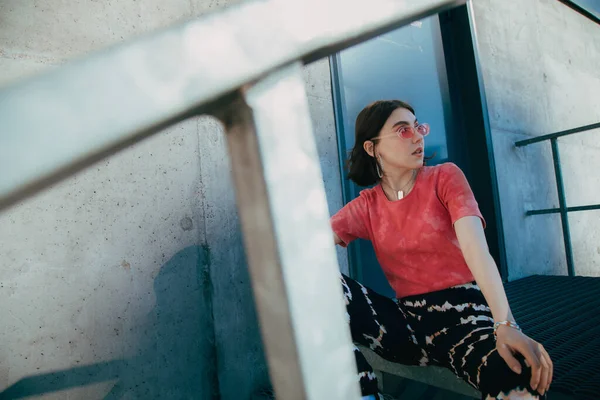 Frau schaut weg, während sie an der Treppe sitzt und den Blick auf die Stadt genießt — Stockfoto