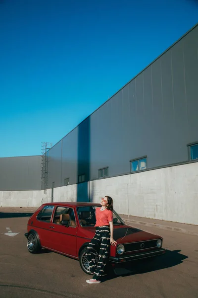 Mädchen wärmt sich in der Sonne, während sie beim Frühlingsspaziergang neben ihrem Auto steht — Stockfoto