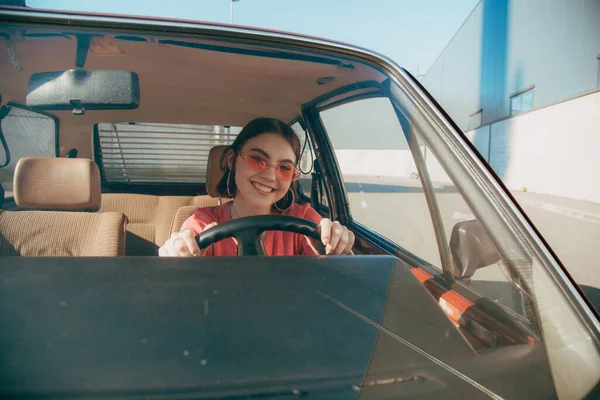 Girl wearing sunglasses sitting behind the wheel in the drivers seat — Stock Photo, Image
