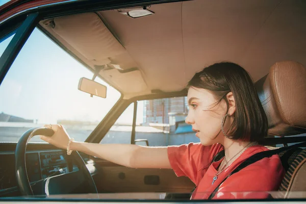 Girl pondering while sitting behind the wheel at the drivers seat — Stock Photo, Image