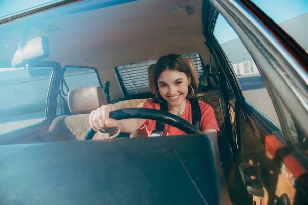 Woman in casual wear looking at the camera while driving a car — Stock Photo, Image