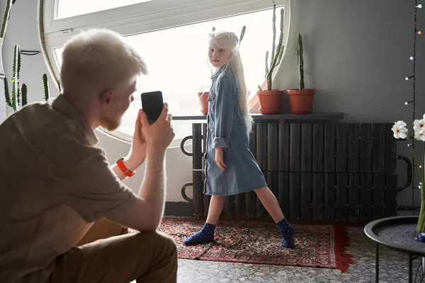 Man shooting at his smartphone his little beautiful daughter while she posing — Stock Photo, Image