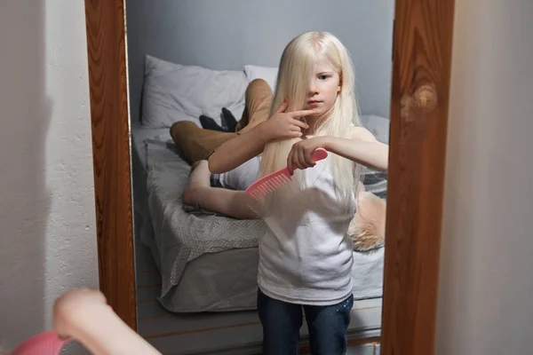 Mädchen kämmt ihr langes Haar und empfindet Vergnügen, während ihr Vater sich entspannt — Stockfoto