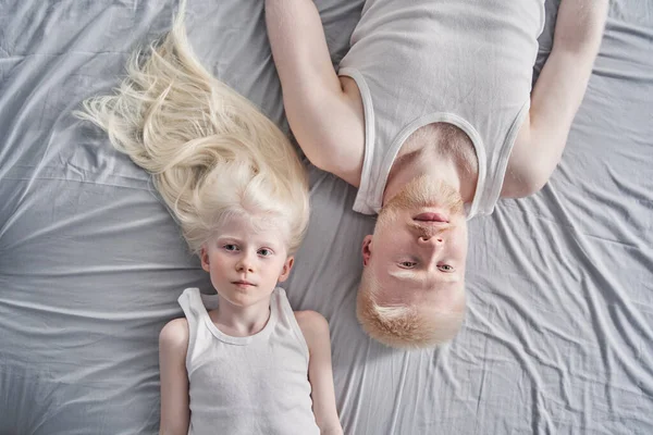 Meisje liggend op de grijze deken met haar albino vader terwijl het doorbrengen van tijd thuis — Stockfoto