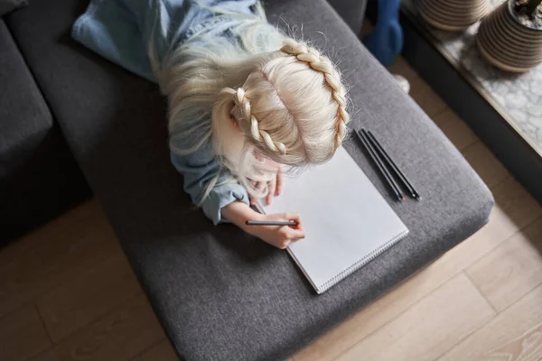 Ragazza prescolare sdraiata sul divano e meditando mentre disegnava sulla carta — Foto Stock