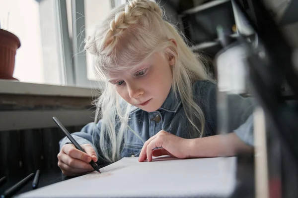 Dívka sedí u stolu v kuchyni a kreslí své mistrovské dílo se soustředěním — Stock fotografie