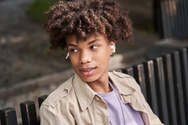 Kulaklık takan bir adam en sevdiği müziği dinlerken ahşap bankta dinleniyor.