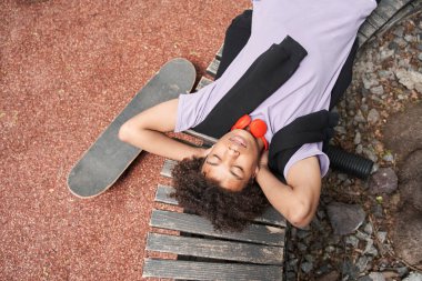 Adam bankta gözleri kapalı yatıyor ve kaykaya bindikten sonra dinleniyor.