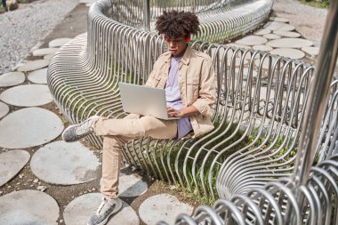 Adam bankta oturup çalışırken ya da ders çalışırken dizüstü bilgisayarda daktilo kullanıyor.