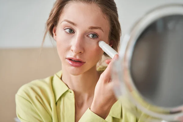 Feminino com vitiligo moles está segurando espelho e olhando para ele enquanto faz massagem facial — Fotografia de Stock