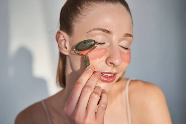 Meisje met vitiligo huid aanbrengen van vlekken onder de ogen met massage roller — Stockfoto