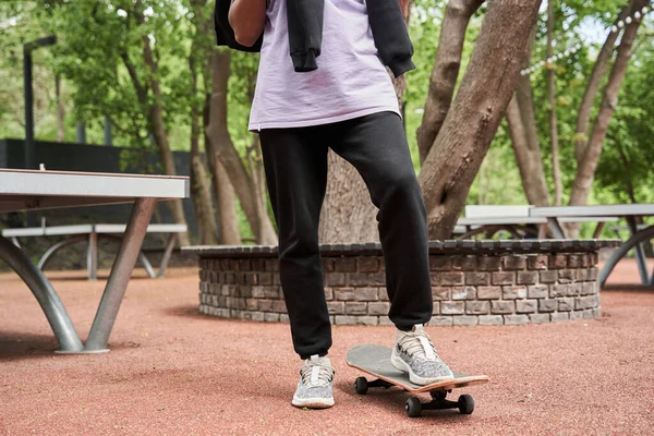 Skateboarder a riposo al parco urbano e portando skateboard sotto la gamba — Foto Stock