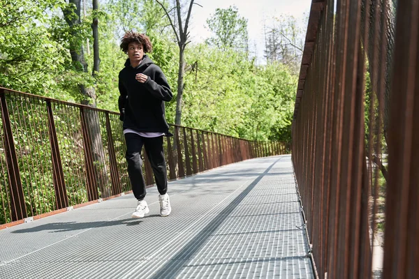 Maschio che corre nel parco e ascolta musica con concentrazione mentre fa jogging — Foto Stock