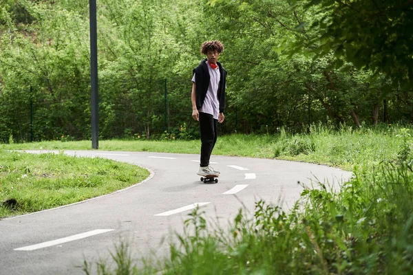Uomo che pratica lo skateboard mentre riposa nel parco verde della sua città — Foto Stock