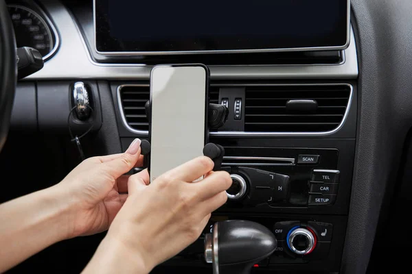 Kobieta umieszczenie smartfona w specjalnym miejscu w samochodzie i przygotowanie się do zmiany nawigatora — Zdjęcie stockowe