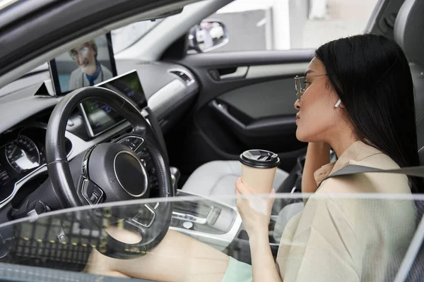 Mujer sentada en el coche y escuchando aconseja a su médico mientras bebe café — Foto de Stock