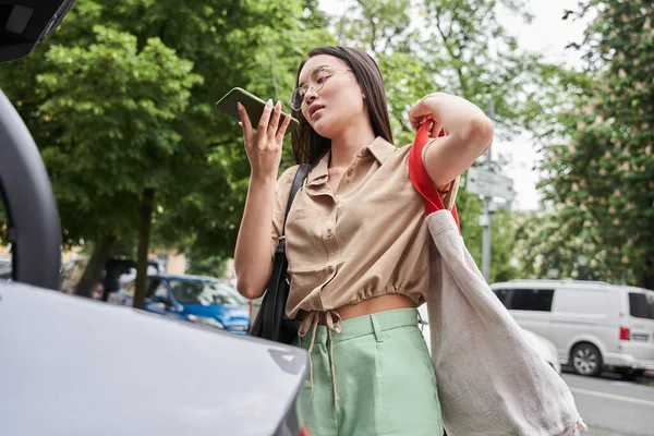 Vrouw die een voicemail opneemt en bij haar auto staat — Stockfoto