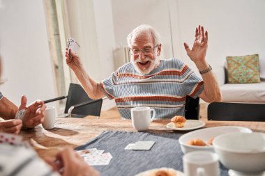 Son sınıf öğrencisi kağıt oyununda kazanırken sevinçten gözlük takıyor.