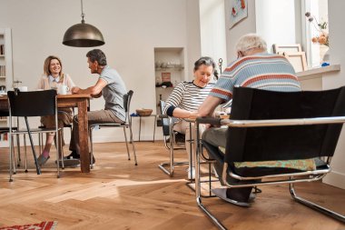 Yaşlı çift dama parçalarına özenle bakıyor.