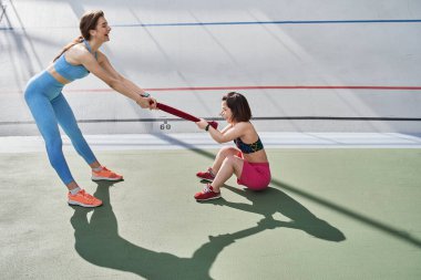 Savaş havlusu gibi çekiştirirken kızlar birbirlerinin önünde duruyorlar.