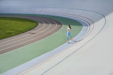 Stadyumda koşan ve sağlıklı ve mutlu hisseden bir kadın.