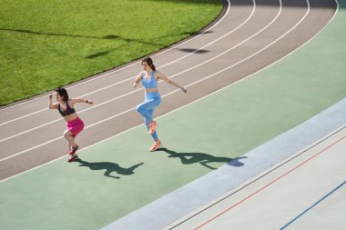 Stadyumda çeşitli kızlar antrenman yapıyor ve koşuyor.