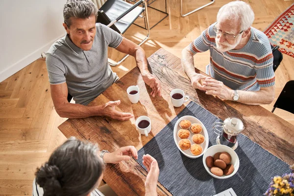 Mensen bespreken iets aan tafel tijdens het smakelijke ontbijt — Stockfoto
