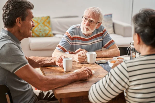Volwassen man luisteren zijn vriend terwijl het drinken van thee en zitten aan de tafel — Stockfoto