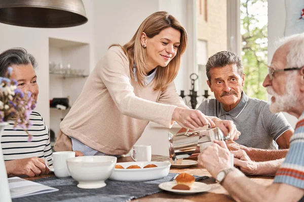 Pflegekraft schenkt dem Rentner Tee ein, während er Zeit im Altersheim verbringt — Stockfoto