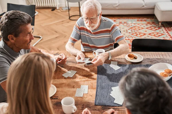 Oudere patiënten van begeleid wonen thuis bijeenkomst aan tafel in de woonkamer — Stockfoto