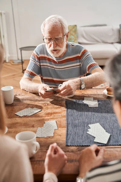 Senior patients of assisted living home gathering at table in living room — Stock Photo, Image