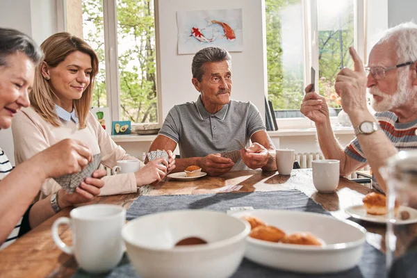 Oudere mensen zitten aan tafel in een verpleeghuis en kletsen — Stockfoto