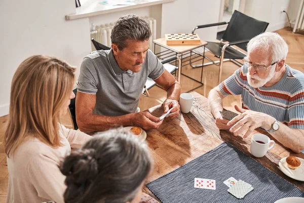 Gepensioneerden die aan tafel zitten en met elkaar aan het kaarten zijn — Stockfoto