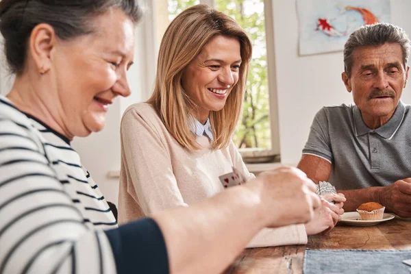 Senior vrouw lachen hardop terwijl zitten aan de tafel met haar verzorger — Stockfoto