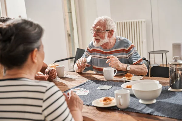 Senior man het dragen van een bril verheugen zich tijdens het winnen bij het kaartspel — Stockfoto