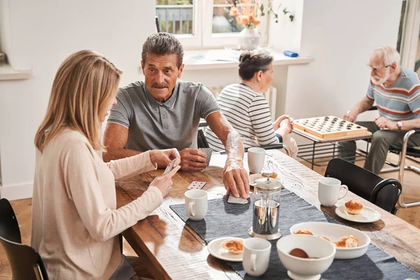 Man gepensioneerde zit aan tafel met zijn verzorger en het drinken van thee — Stockfoto