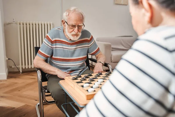 Aged couple playing at the checkers at the nurse house — Stock Photo, Image