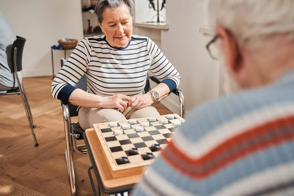 연로 한 부부 가집에서 간호사와 함께 체커 놀이를 하는 모습 — 스톡 사진