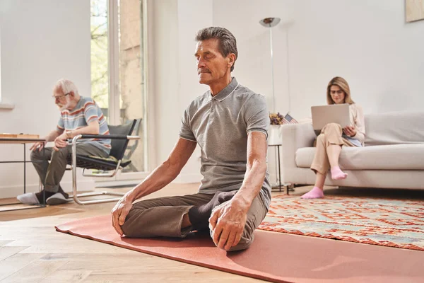 Hombre con ropa casual meditando y sentado en pose de loto con los ojos cerrados — Foto de Stock