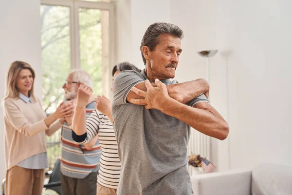 Älterer Mann streckt beim Training im Pflegeheim während des Vormittagstrainings die Hände — Stockfoto