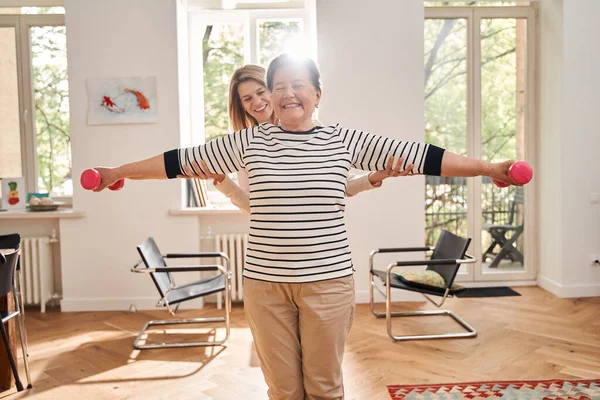Seniorin turnt mit Pflegerin im Wohnzimmer — Stockfoto