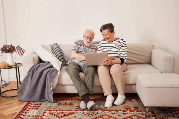 Senior par känslomässigt prata med släktingar medan du sitter med bärbar dator — Stockfoto