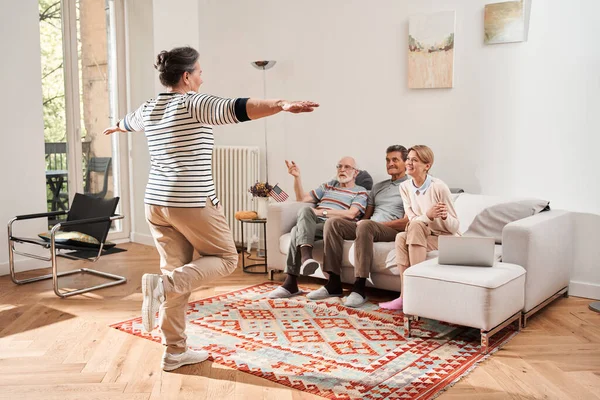 Vrouw die voor de gepensioneerden en verzorgers op de bank zit en speelt — Stockfoto