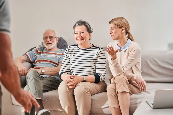 Oudere mensen en hun verzorger zitten op de bank en denken na — Stockfoto