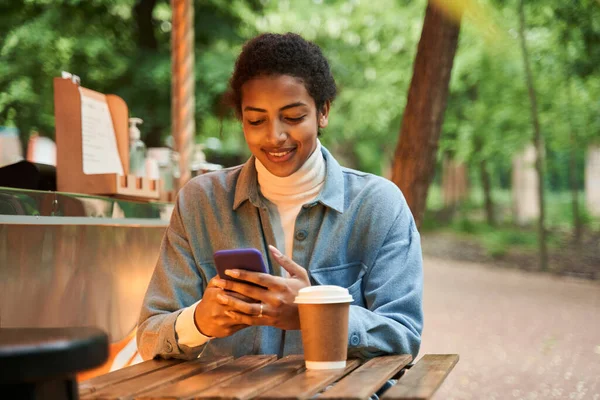 Mulher olhando para seu smartphone e beber café enquanto está sentado no café — Fotografia de Stock