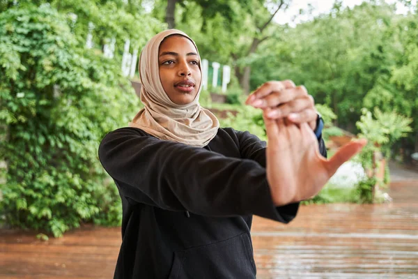 Kobieta w hidżabie rozgrzewa się przed porannym treningiem w wiosennym parku — Zdjęcie stockowe