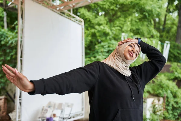 Kobieta w hidżabie rozgrzewa się przed porannym treningiem w wiosennym parku — Zdjęcie stockowe